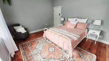 A bedroom with a bed, nightstands, a chair, and a door.