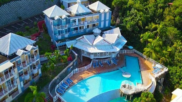 A resort with a large pool, multiple buildings, and lush greenery. - Studio "le pipiri" swimming pool sea view secure residence (La Trinité)