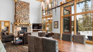 A cozy living room with a stone fireplace, wooden dining table, and comfortable seating. - Private Waterdance Home with all the Amenities!! (Frisco)