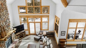 A spacious living room with a stone fireplace, large windows, and a cozy seating area. - Private Waterdance Home with all the Amenities!! (Frisco)