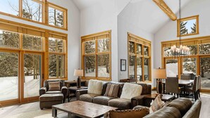A spacious living room with large windows, leather furniture, and a chandelier. - Private Waterdance Home with all the Amenities!! (Frisco)