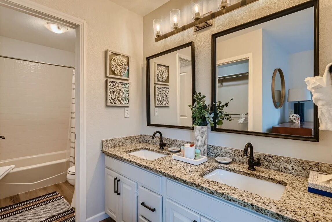 A bathroom with two sinks, a large mirror, and decorative wall art.