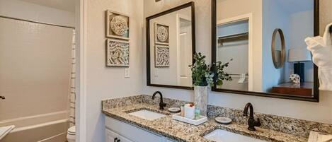 A bathroom with two sinks, a large mirror, and decorative wall art.
