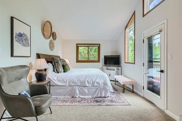 A bedroom with a bed, a chair, a TV, and a window.