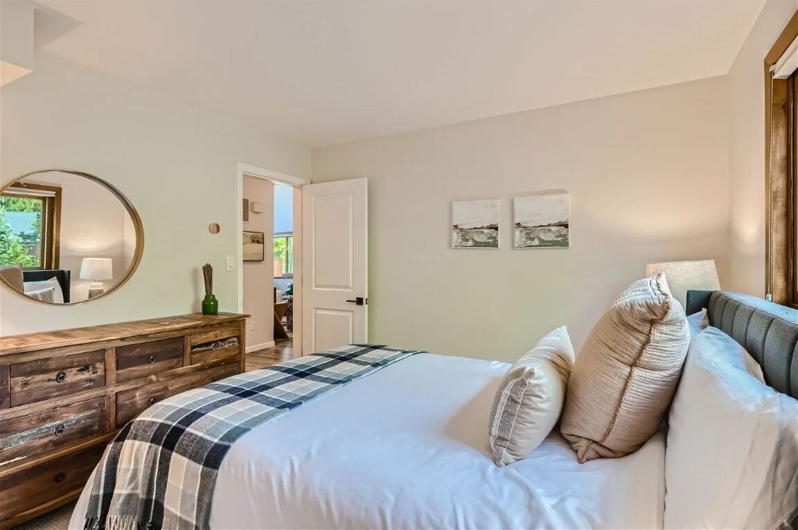 Une chambre à coucher comprenant un lit, une commode et une porte donnant sur une autre pièce.