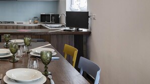 A modern kitchen with white cabinets, a dining table set with glassware and plates, and a large window providing natural light. - Beauty Design in the Center by Wonderful Italy (Genoa)
