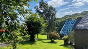 A well-maintained garden with a variety of trees and shrubs, a clear sky, and a modern building with large windows.