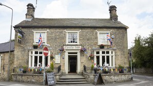 A stone building with a sign reading "Castle Inn" and a signboard for "The Castle Inn" with a price of £49. - Castle Inn By Greene King Inns (Bakewell)