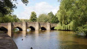 A stone bridge over a calm river with ducks swimming. - Castle Inn By Greene King Inns (Bakewell)