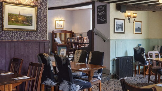 A traditional inn with wooden furniture, a framed landscape painting, and a sign indicating ladies' and gentlemen's toilets. - Castle Inn By Greene King Inns (Bakewell)