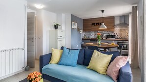Un saló modern amb un sofà, taula de dinar amb cadires i una zona de cuina al fons.