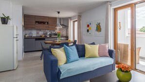 Un saló modern amb un sofà, una taula de dinar i una cuina al fons.