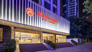 Un hotel con fachada moderna, un logotipo destacado y una entrada bien iluminada.