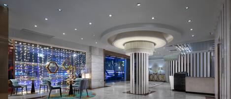 A modern lobby with a reception desk, seating area, and a decorative column.