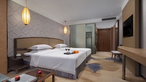Habitación de hotel con dos camas, un escritorio, un televisor y un baño.