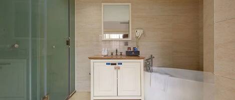 A bathroom with a glass shower enclosure, a white vanity with a mirror, and a white bathtub.