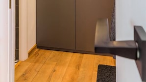 Armari tancat amb dues portes i una nansa, sòl de fusta i paret blanca.