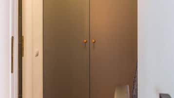 Ein geschlossener Kleiderschrank mit zwei Türen und Griff, ein Holzboden und eine weiße Wand.