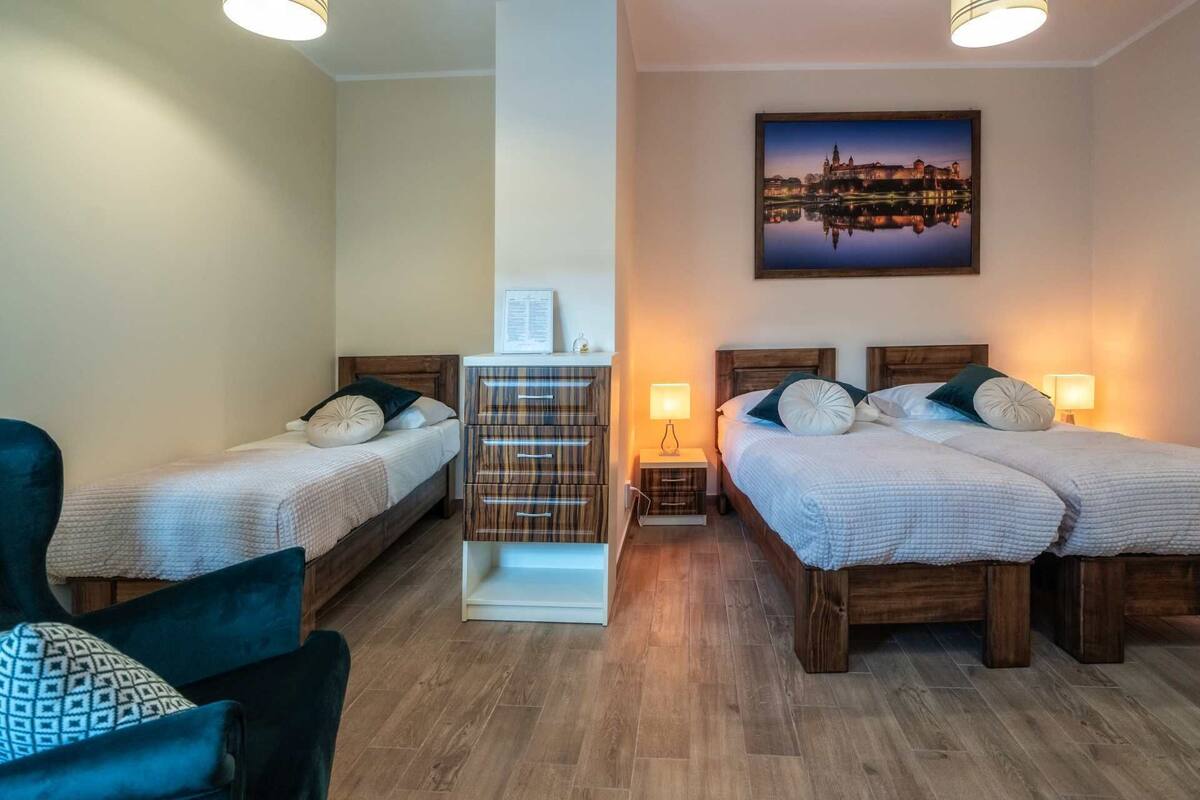 A hotel room with two single beds, a wooden cabinet, a chair, and a framed picture on the wall.