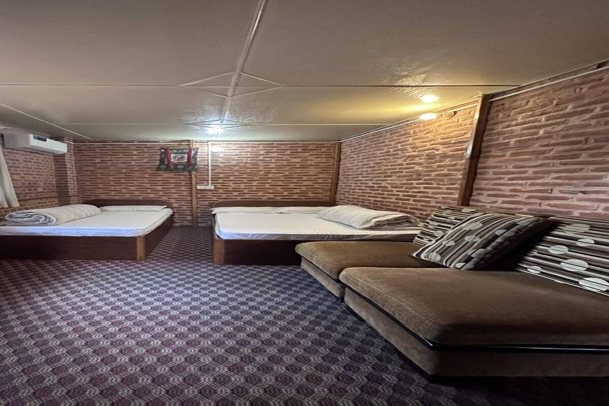 Een kamer met twee bedden, een bank, een eettafel en wanden met een baksteenmotief.