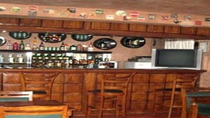 Un coin bar avec des meubles en bois, un téléviseur et une variété de bouteilles.