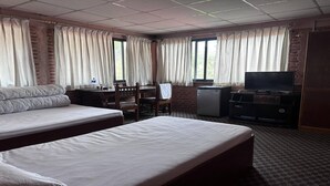 Une chambre d’hôtel avec deux lits, un bureau, une télévision et une fenêtre avec des rideaux.