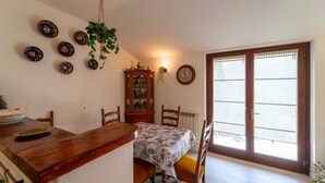Un comedor con una mesa de madera, sillas, un reloj y platos decorativos en la pared.