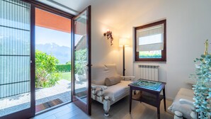 Una habitación con sofá, una mesita, una lámpara y vistas a montañas a través de un ventanal corredero.
