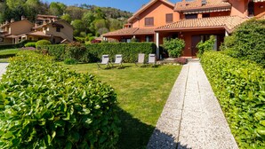 Un edificio residencial con varias viviendas, un sendero pavimentado y abundante vegetación.