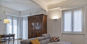 Un salon moderne avec un canapé d’angle, un meuble en bois et un coin repas comprenant une table et des chaises.