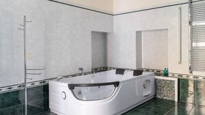 A modern bathroom with a freestanding bathtub, a glass shower enclosure, and a tiled floor.