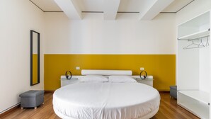 A modern bedroom with a round bed, a yellow accent wall, and a minimalist design.