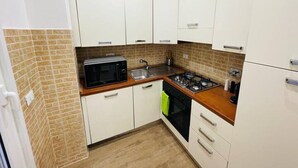 A compact kitchen with white cabinets, a microwave, a sink, and a stove. - Home Vatican Oasis (Roma)