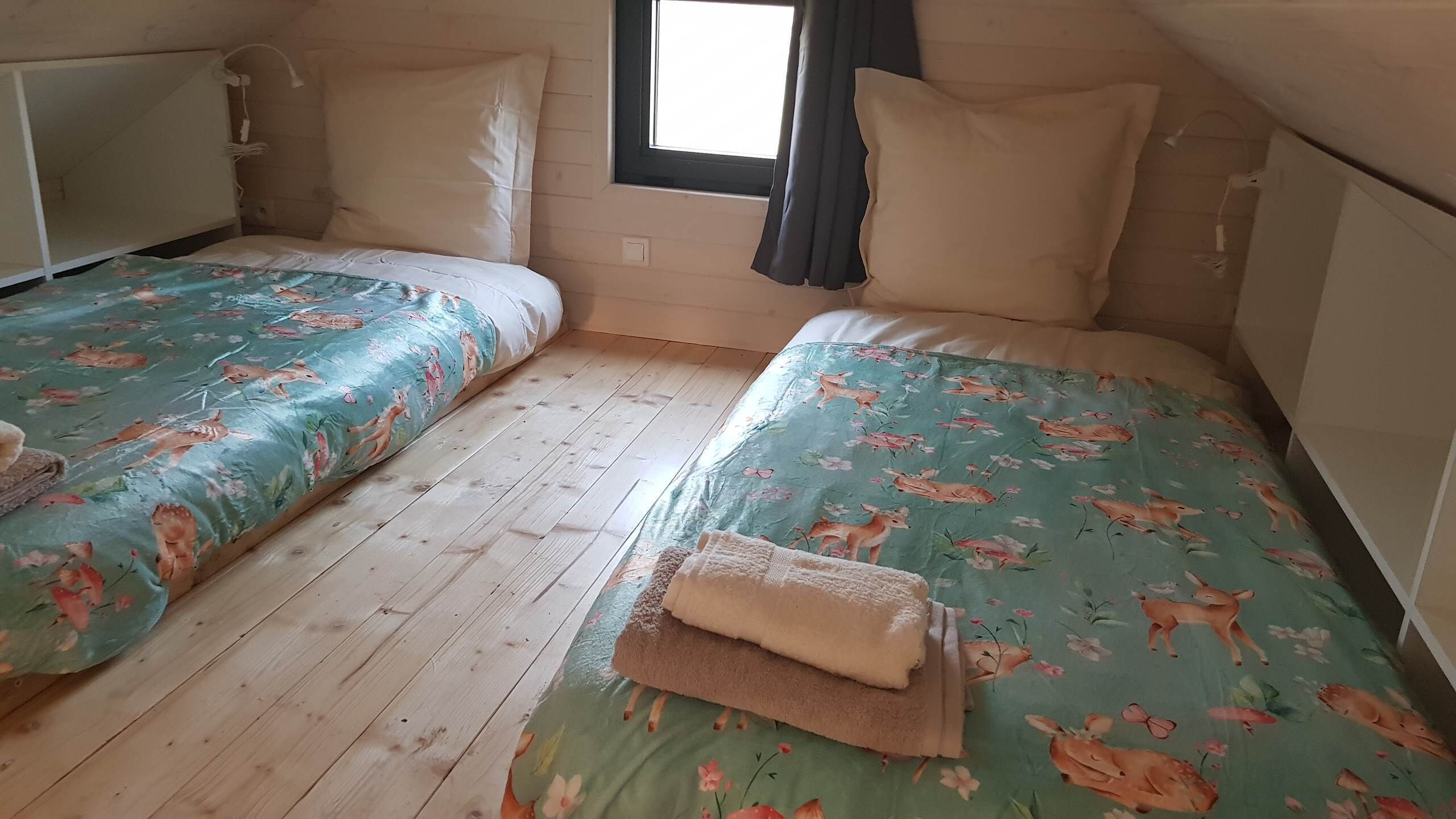 Een kamer met twee bedden, een raam met gordijnen en een radiator.