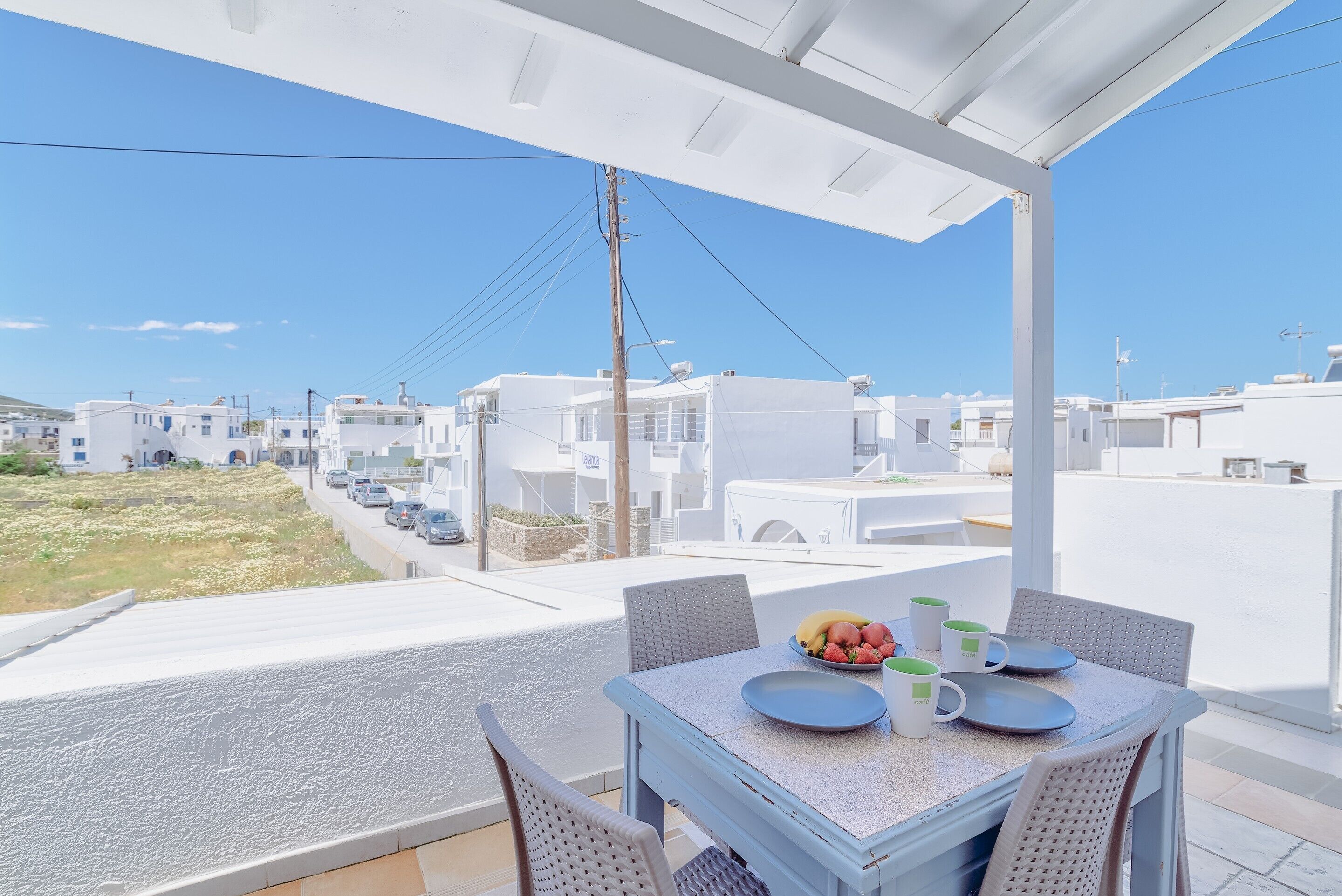 Un balcón con una mesa para dos, con vistas a una zona residencial de edificios blancos.