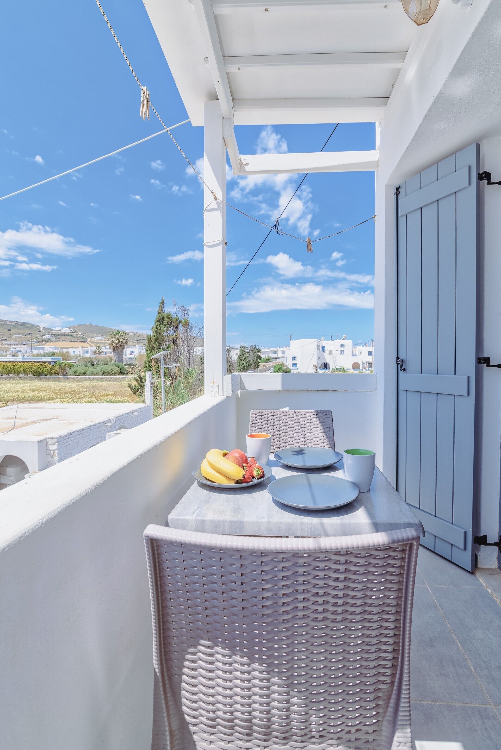 Een balkon met een gedekte tafel voor twee, met uitzicht op een kustlandschap.