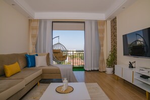 Una sala de estar moderna con un sofá, una mesa de centro, un televisor y un balcón con una silla colgante.