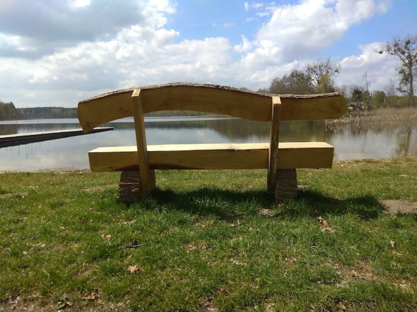 Eine Holzbank am See unter einem klaren Himmel.