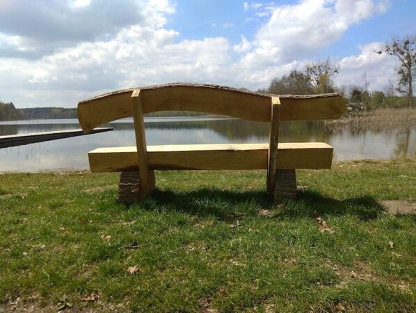 A wooden bench by a lake with a clear sky.