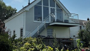 Una casa moderna de dos pisos con un balcón grande y una chimenea.