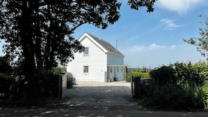 A white house with a gravel driveway and a wooden gate. - Spires (Truro)