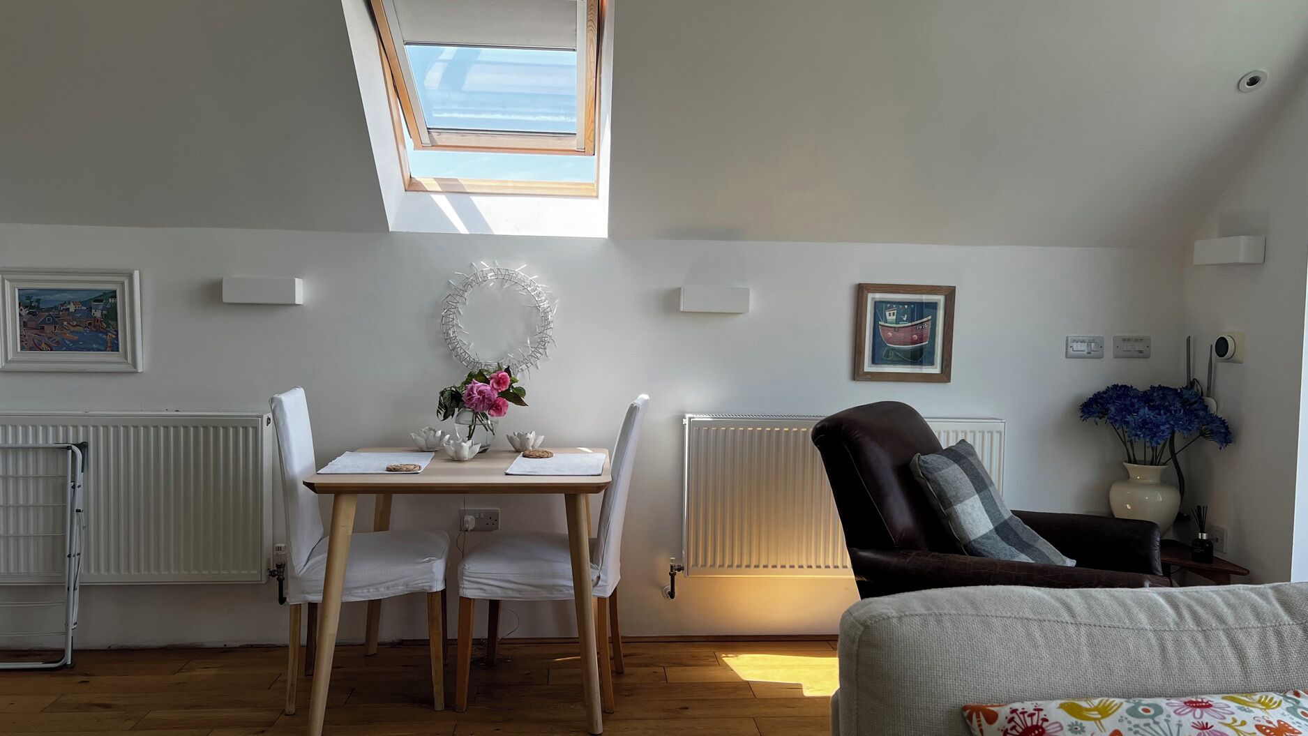A room with a dining table, chairs, a radiator, a window, and a couch.