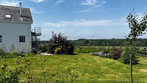 A house with a white exterior, a visible staircase, and a garden with various plants and flowers. - Spires (Truro)