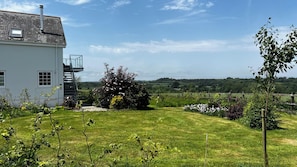A house with a white exterior, a visible staircase, and a garden with various plants and flowers. - Spires (Truro)