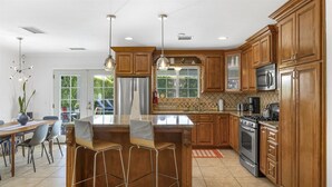 Una cocina moderna con armarios de madera, electrodomésticos de acero inoxidable y una isla central con taburetes de bar.
