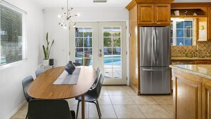Una cocina moderna con un refrigerador de acero inoxidable grande, armarios de madera y un comedor con mesa y sillas.