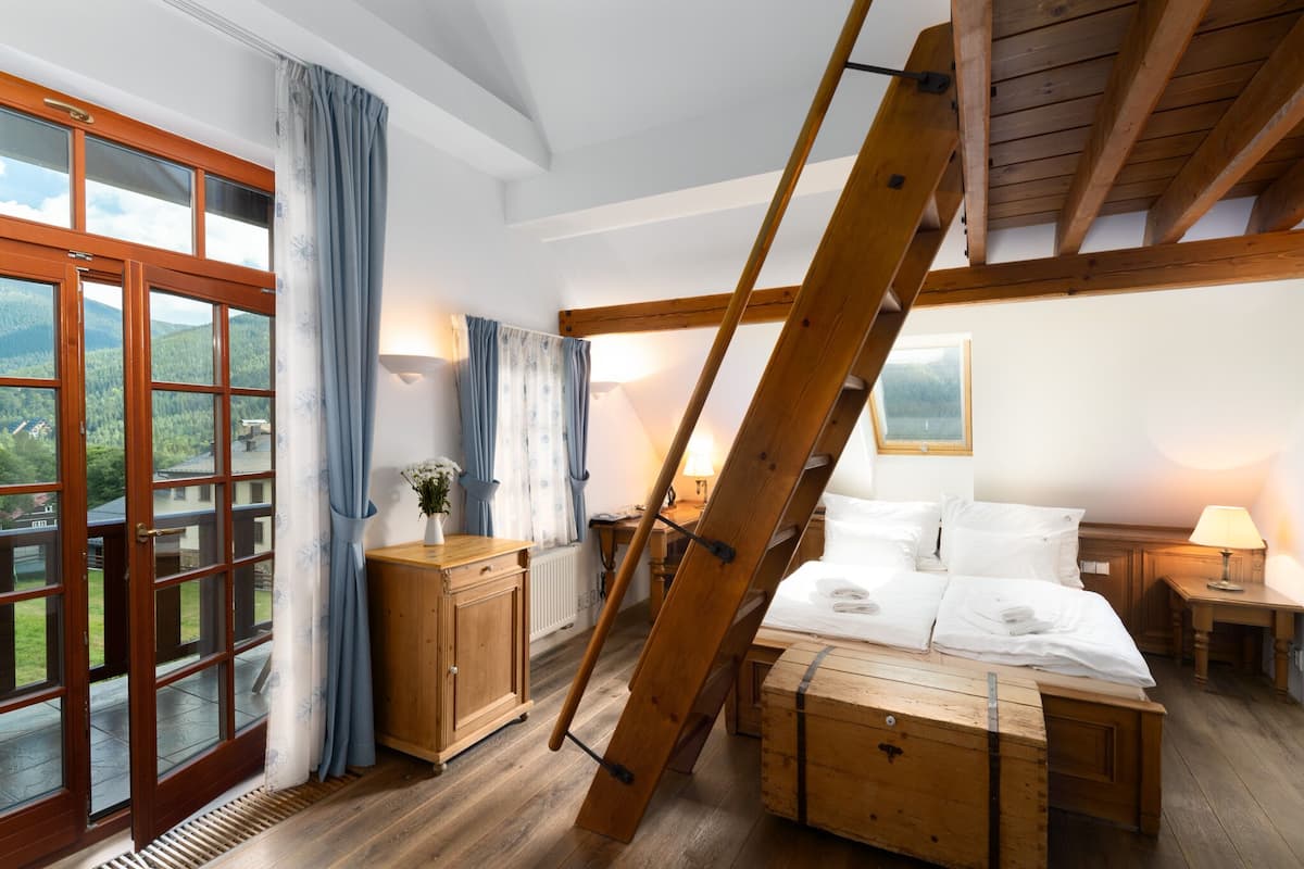 Um quarto com cama de madeira, mesa de cabeceira, cômoda e janela com cortinas.