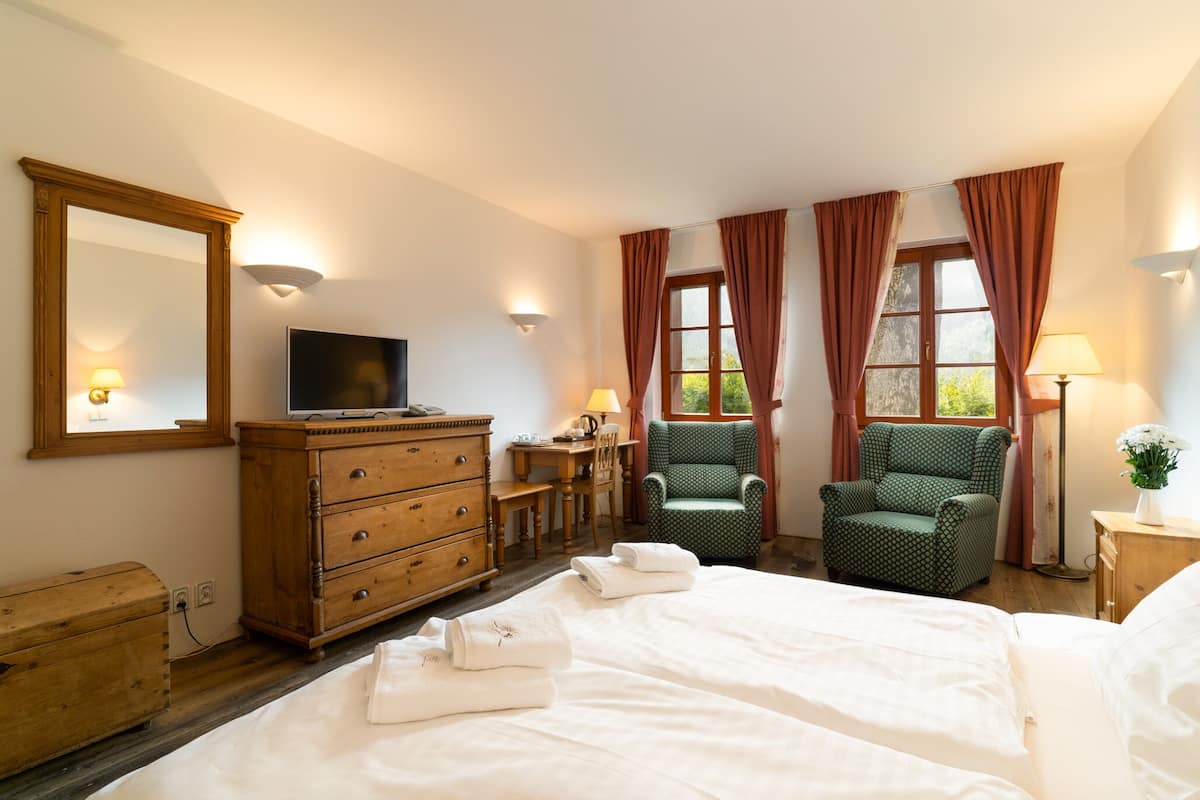 Quarto de hotel com cama, cômoda, televisão, cadeira e escrivaninha.