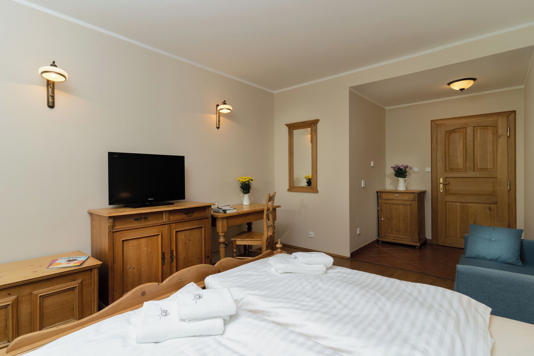 Ett hotellrum med en säng, en tv, trämöbler och en spegel.