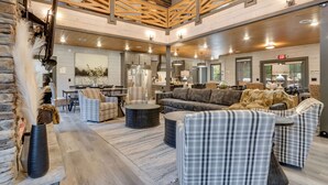 A spacious living area with a high ceiling, wooden beams, and a modern kitchen in the background.